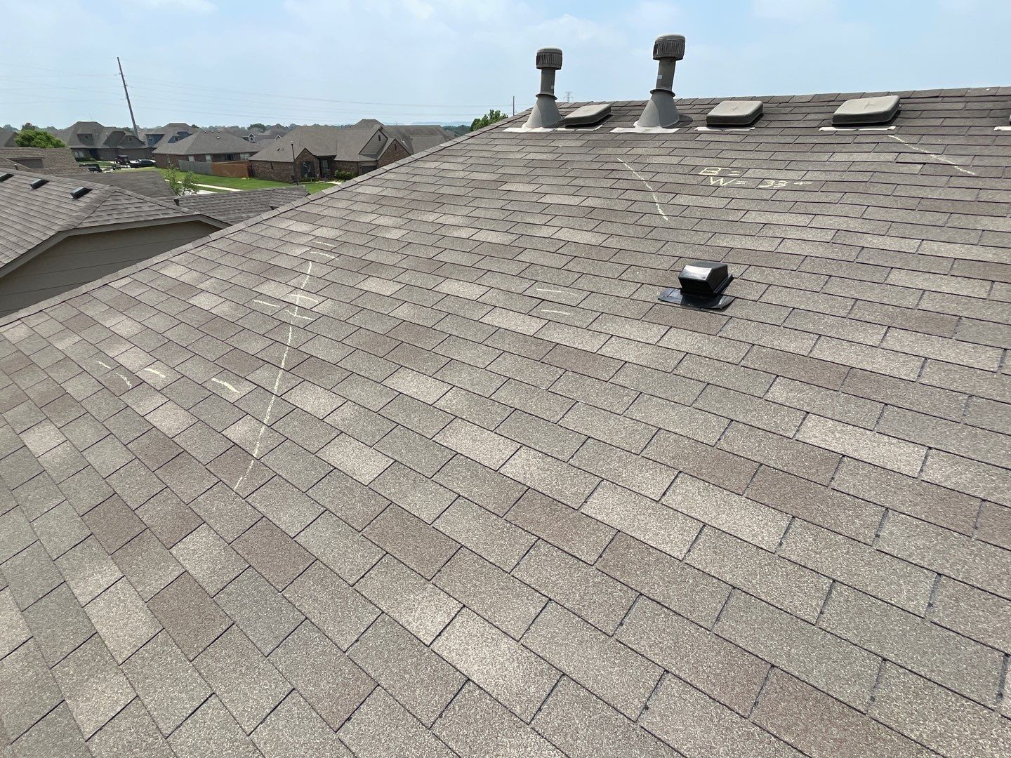 Chalk marks indicating hail damage on shingles during AJC storm inspection